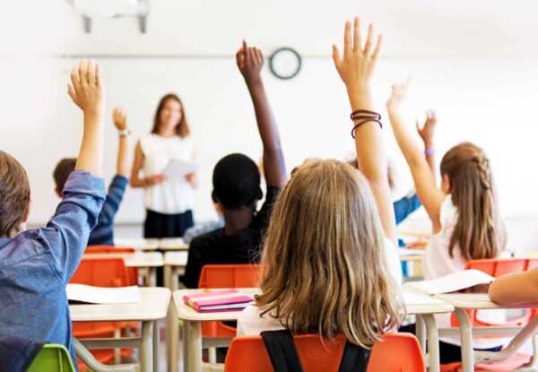 Teach students important procedures like raising hands to speak on the first day of school.